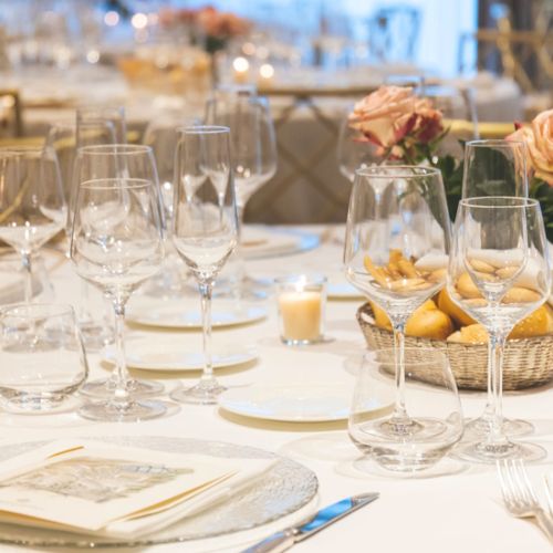 Elegant table setting with wine glasses, candles, and rose centerpieces for a formal event.