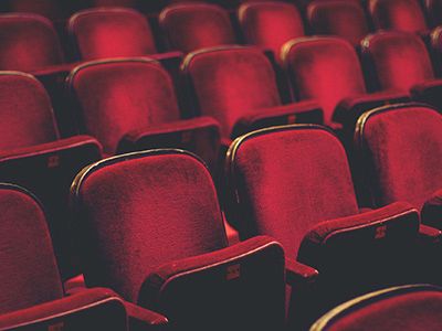 Rows of red theater seats, plush and empty, fading into the background. Always ending the sentence.